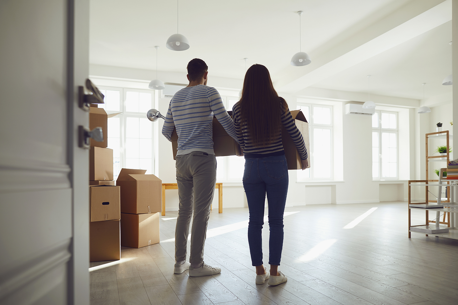 A couple carrying boxes inside a home.